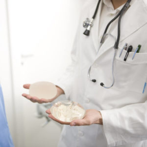 Doctor holding a silicone and saline breast implant