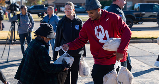 A photo of a local Oklahoma City volunteer at the 2025 Annual Day of Kindness handing out turkeys to the community.